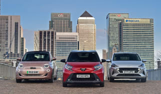 Toyota Aygo X vs Hyundai i10 vs Fiat 500 group test - three cars in front of London city skyline