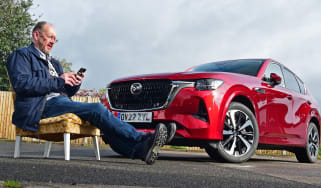 Auto Express chief sub-editor Andy Pringle sitting reading his phone in front of Mazda CX-60